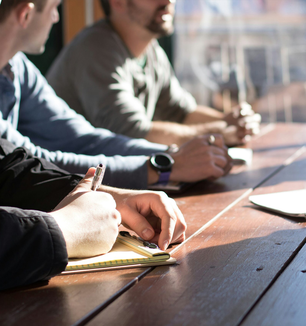 Trainees maken aantekeningen bij een teamoverleg